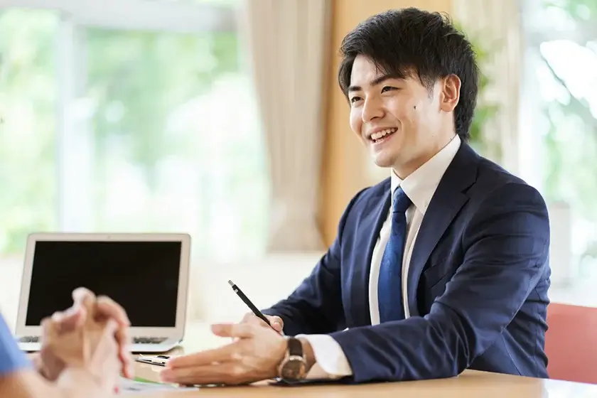 お客様相手に話をするスーツを着た男性の写真